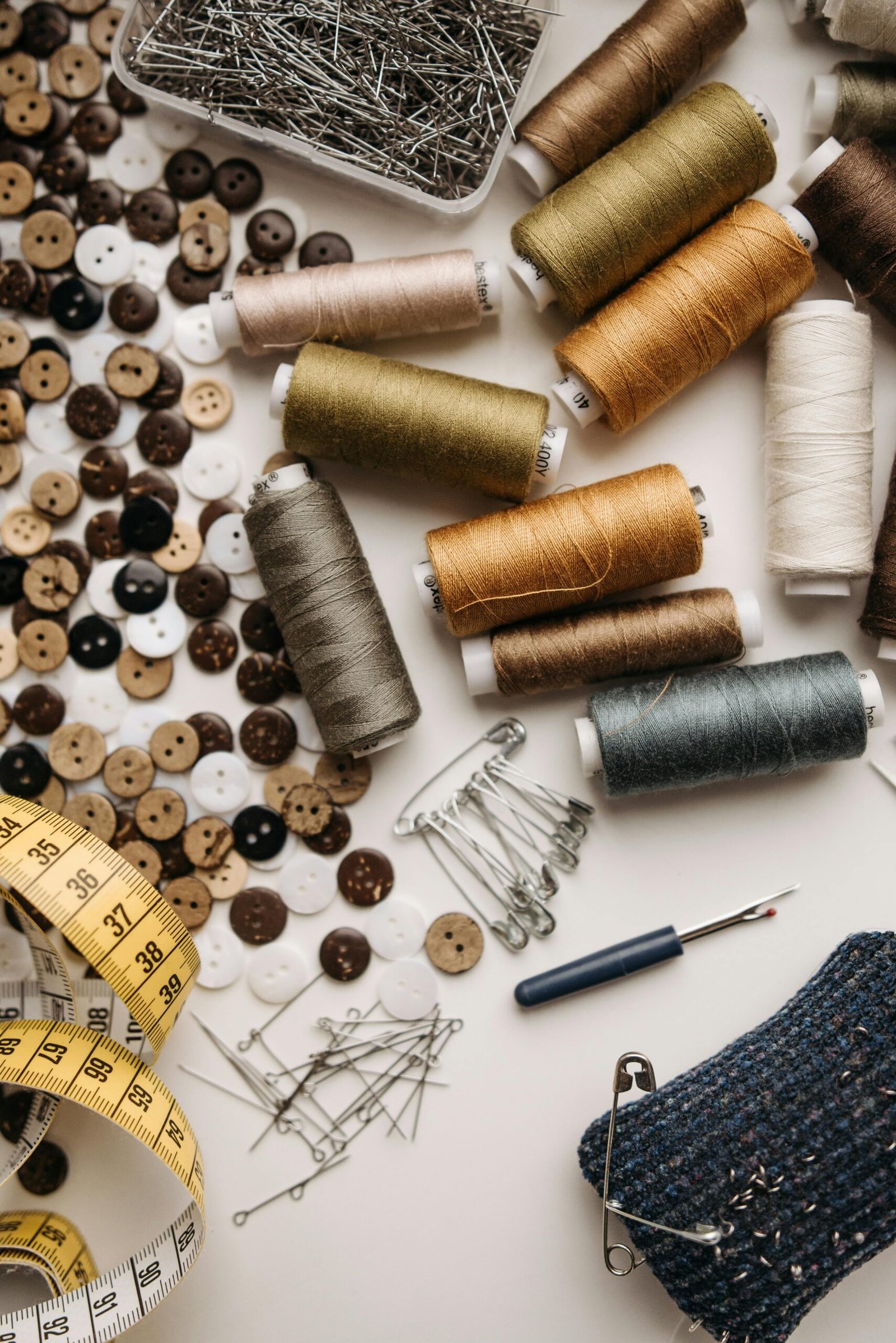 Colorful sewing threads, buttons, pins, and tools laid out for crafting.